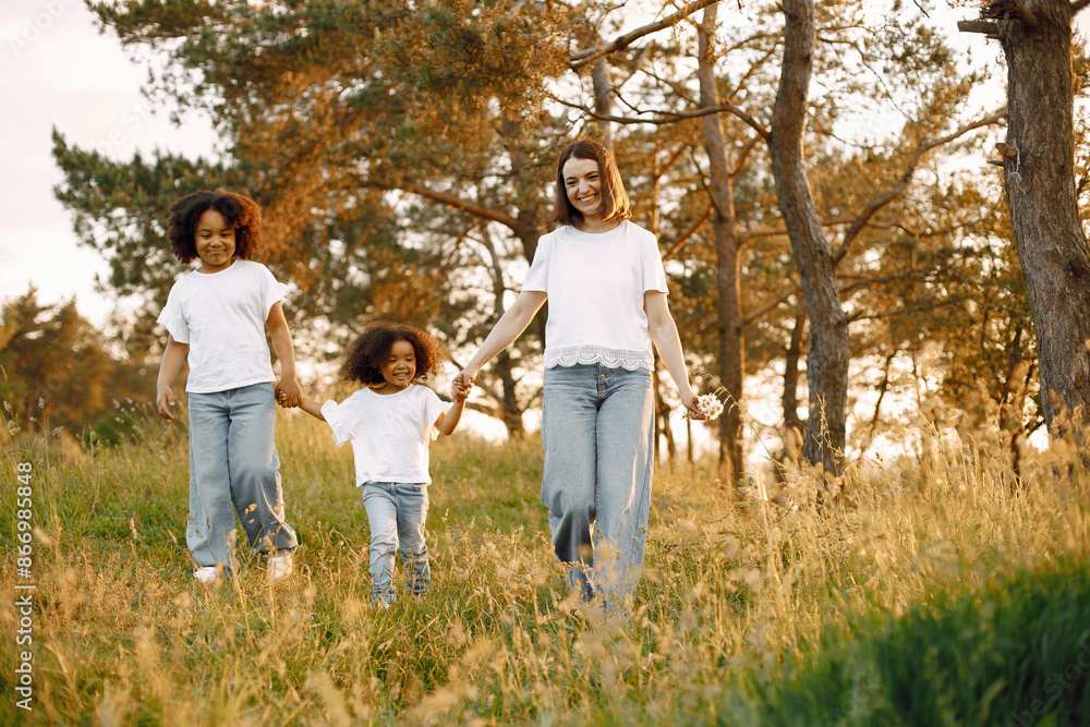 Caucasian mother and two her mixed race daughters walking in a park Caucasian mother and two her mixed race daughters walking in a park
