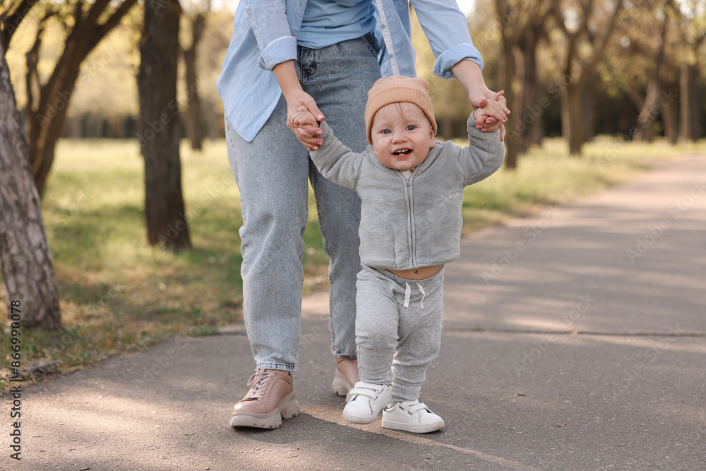 Fototapeta premium Mother teaching her baby how to walk outdoors, closeup