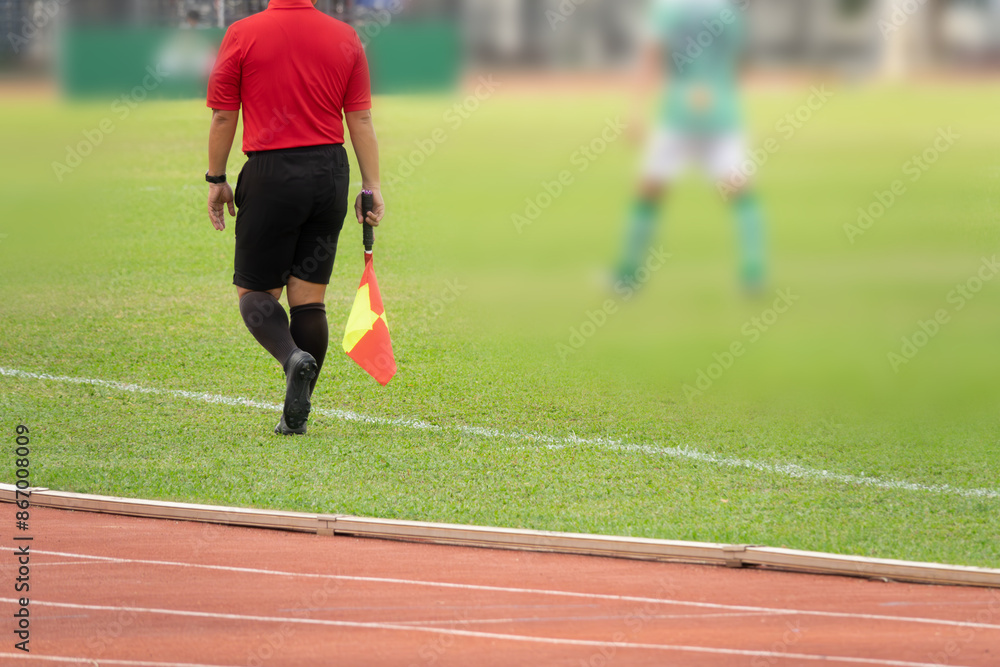 Obraz premium A referee is walking on a track with a yellow and red flag in his hand