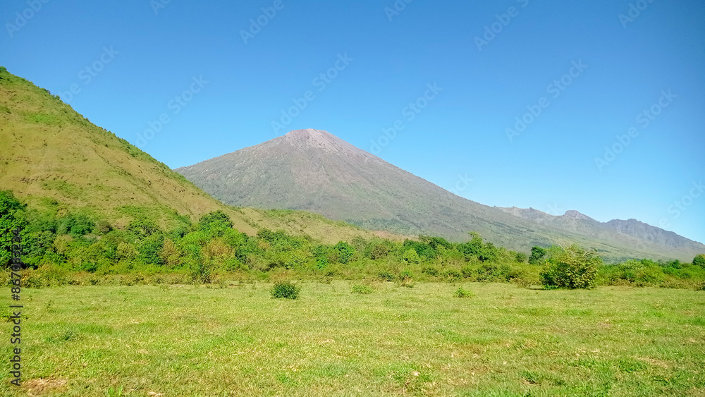 view of Mount Rinjani from the Dandaun savanna hills. the landscape is for hiking and outdoor lifestyle concept. beautiful natural scenery view of Mount Rinjani from the Dandaun savanna hills. the landscape is for hiking and outdoor lifestyle concept. beautiful natural scenery