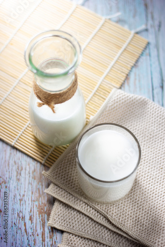 Top view glass and bottle of tasty milk on wooden table