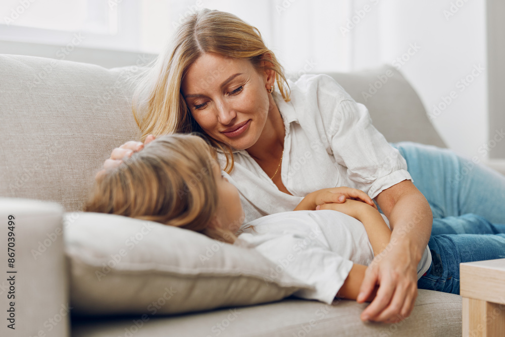 Mother and daughter bonding moment on a cozy couch, sharing smiles and laughter in a warm, loving embrace Mother and daughter bonding moment on a cozy couch, sharing smiles and laughter in a warm, loving embrace