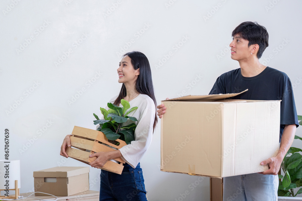 Young Couple Moving into New House, Carrying Boxes and Plants, Starting Fresh in Their Modern Home Young Couple Moving into New House, Carrying Boxes and Plants, Starting Fresh in Their Modern Home