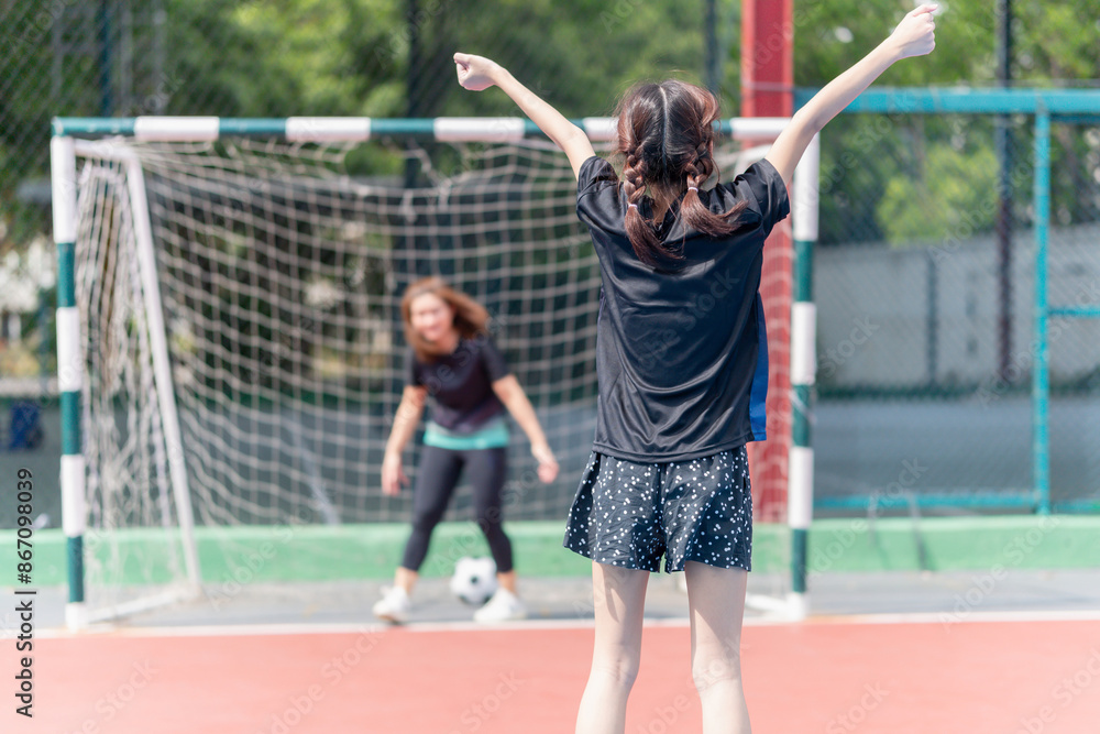 Mom with a child playing football in the urban outdoor futsal court Mom with a child playing football in the urban outdoor futsal court