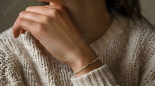 A detailed close-up of a woman's wrist adorned with a slender, silver bracelet, showcasing the elegance of minimalist jewelry. all within a minimalist composition.