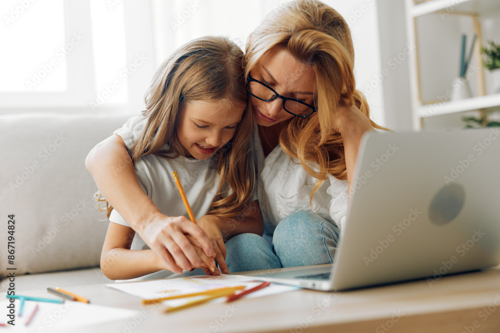Mother and daughter collaborating on a laptop at a table filled with colored pencils, enjoying creative time together Mother and daughter collaborating on a laptop at a table filled with colored pencils, enjoying creative time together