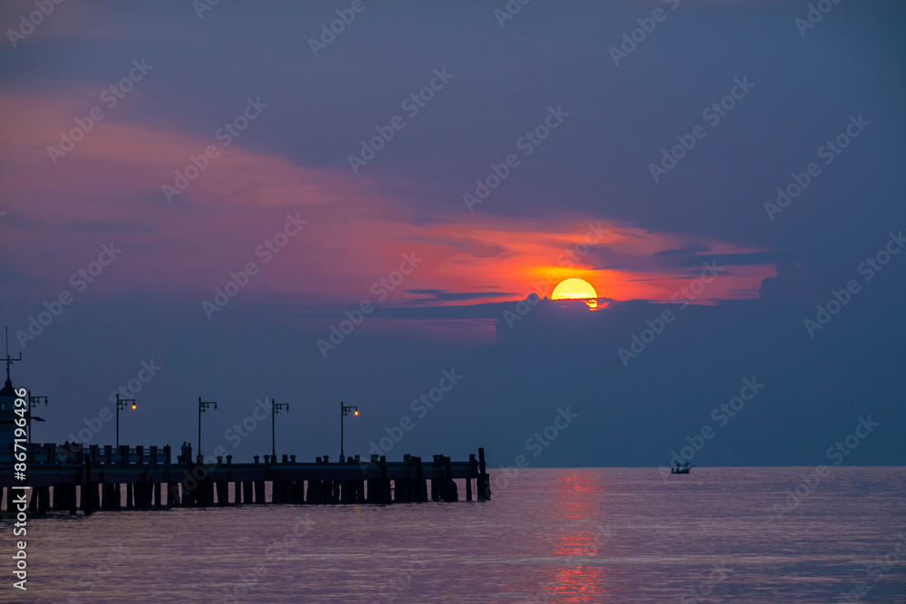 Obraz premium Fiery orange sun dips below the horizon, painting the sky and water in a breathtaking summer sunset