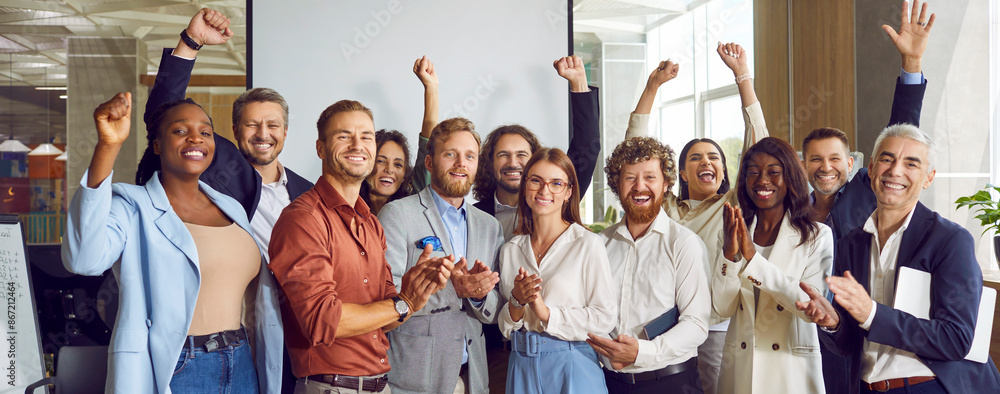 Obraz premium Group of multiethnic happy business people men and women looking at the camera, smiling and applauding. Company employees team or a group of staff standing in the office cheerfully. Banner.