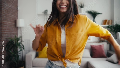 Video of cute young woman dancing while looking to camera in the living room at home