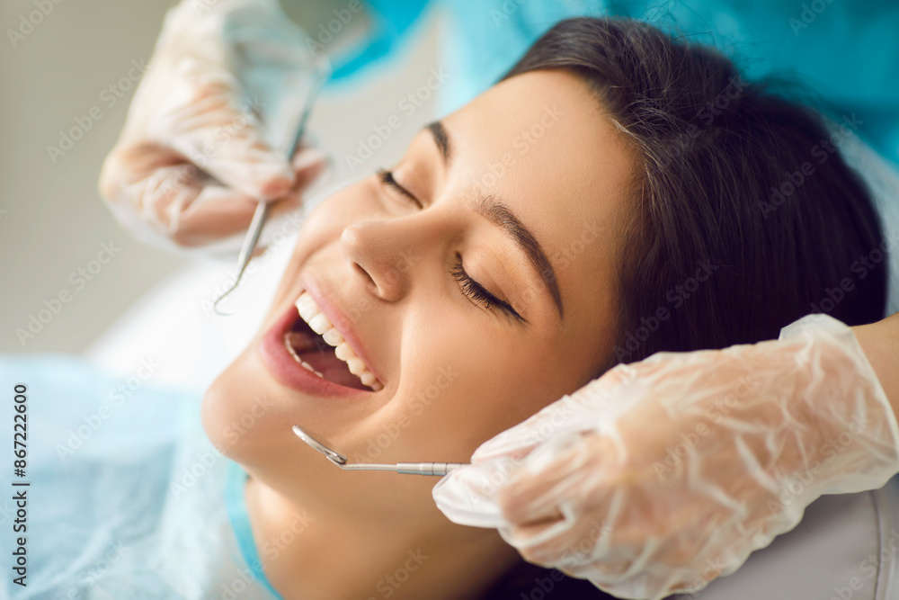 Woman patient having teeth examined by a dentist doctor using an instrument during a visit to the hospital. Dental check up showing importance of dental examinations for maintaining oral health. Woman patient having teeth examined by a dentist doctor using an instrument during a visit to the hospital. Dental check up showing importance of dental examinations for maintaining oral health.