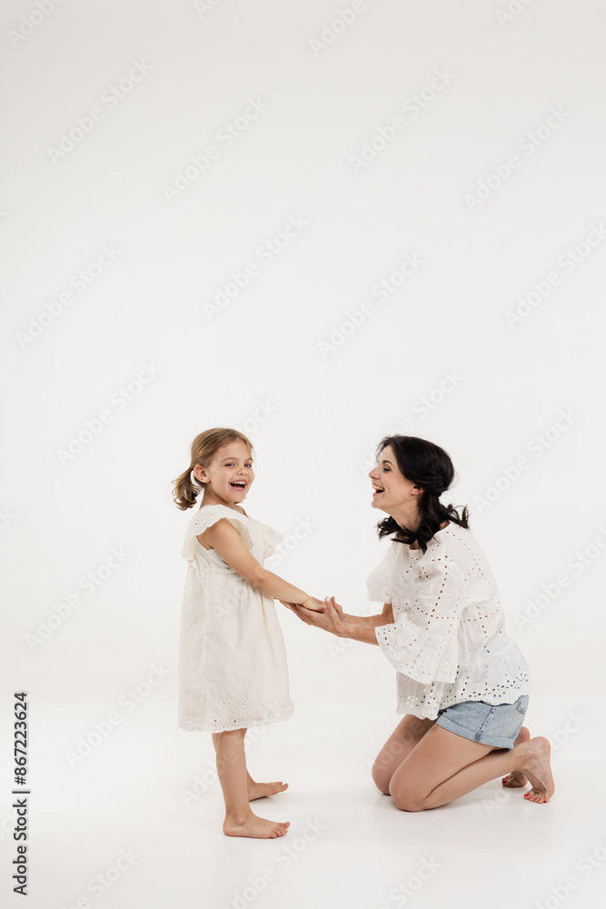 mother in summer clothes has fun with cute little girl. Mother and little daughter isolated on white background. Mother's day, love, family, parenthood, childhood concept. mother in summer clothes has fun with cute little girl. Mother and little daughter isolated on white background. Mother's day, love, family, parenthood, childhood concept.