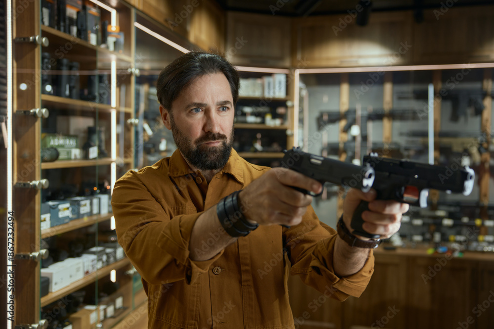 Obraz premium Portrait of mature male in shop merchant with two handguns aiming