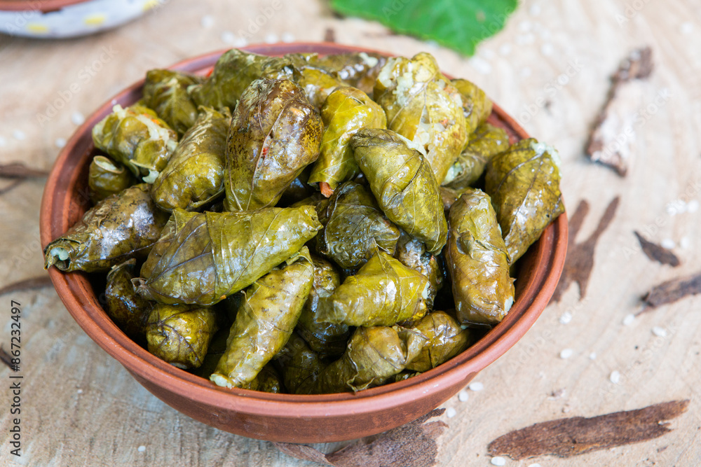 Dolma a stuffed grape leaves in a clay bowl on wooden background Dolma a stuffed grape leaves in a clay bowl on wooden background