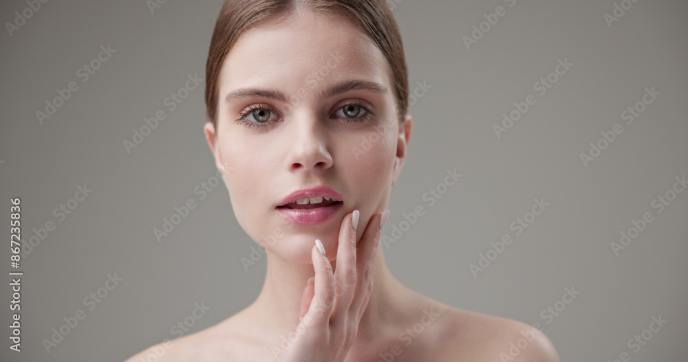Beauty, health, cosmetics, anti-aging therapy and skin care concept - young beautiful brunette Caucasian woman posing and looking at the camera with a calm confident look like in a mirror Beauty, health, cosmetics, anti-aging therapy and skin care concept - young beautiful brunette Caucasian woman posing and looking at the camera with a calm confident look like in a mirror