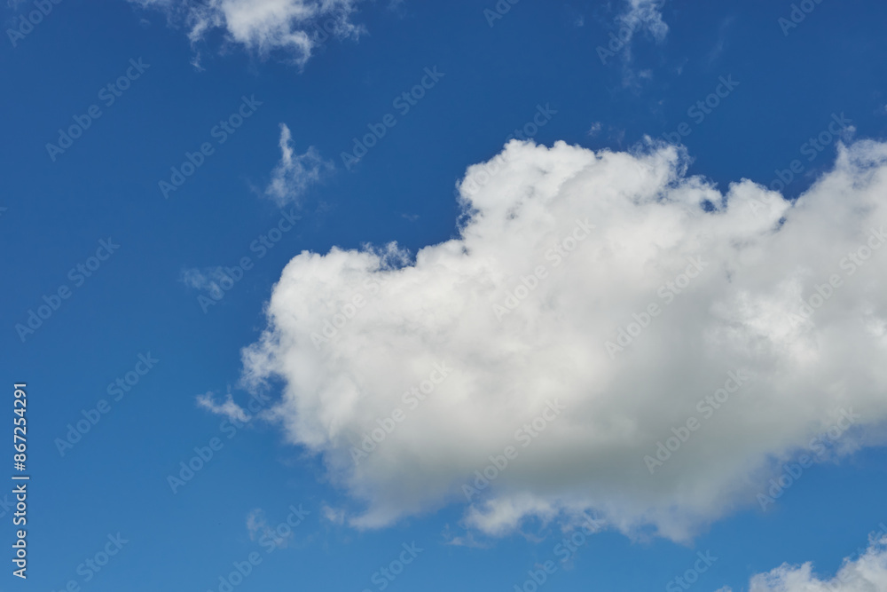 White fluffy clouds in the sky. Blue sky and cloud cover on a sunny summer day. Empty background, copy space White fluffy clouds in the sky. Blue sky and cloud cover on a sunny summer day. Empty background, copy space
