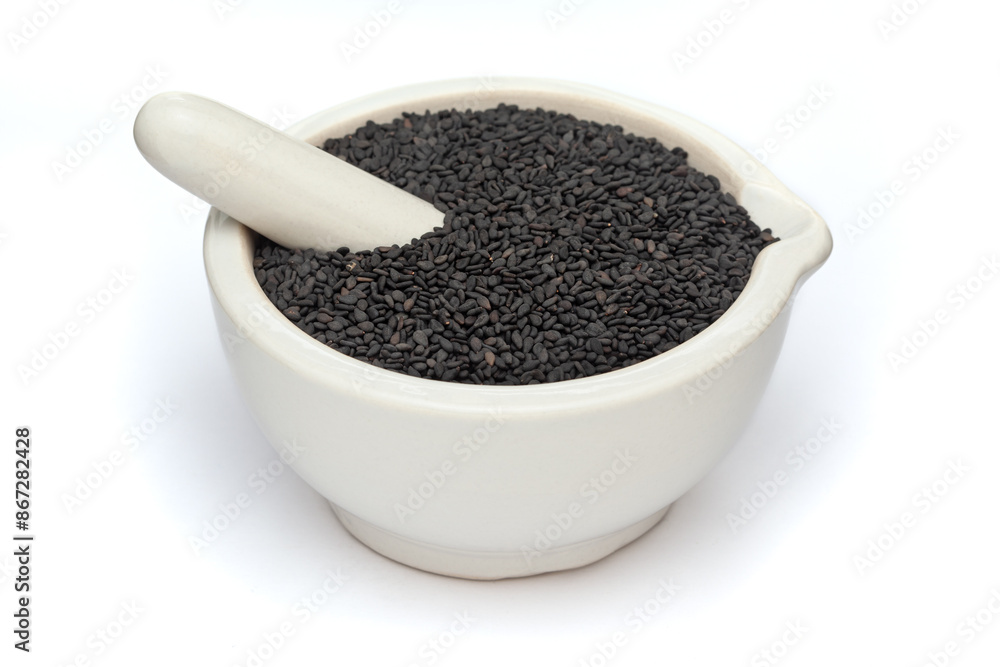 Close-up of Dry Organic Black Sesame (Sesamum indicum) Seeds, in white ceramic mortar and pestle, isolated on a white background. Close-up of Dry Organic Black Sesame (Sesamum indicum) Seeds, in white ceramic mortar and pestle, isolated on a white background.