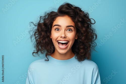 happy young woman in turquoise sweater looking up on blue background