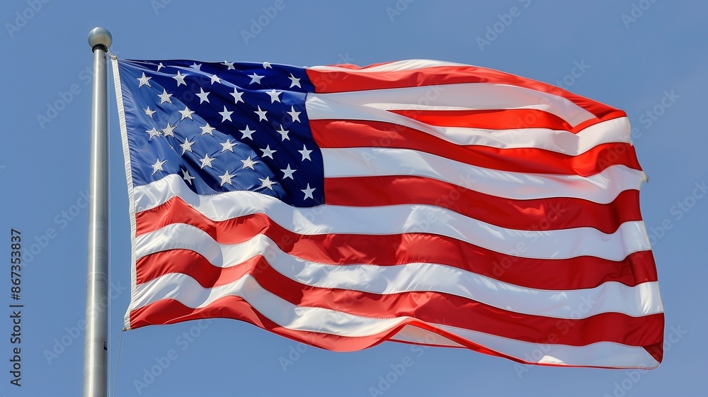 Obraz premium A dynamic capture of the American flag in mid-wave, its colors vibrant and bold against a clear blue sky.