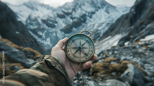 Person holding compass in hand on winter mountain background.