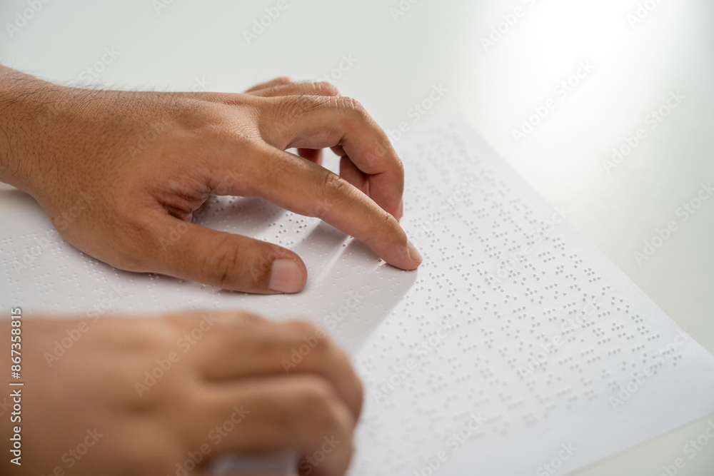 Hand of a blind person reading some braille text on page paper to learn. Finger of blind student touching the braille alphabet Code on sheet. Hand of a blind person reading some braille text on page paper to learn. Finger of blind student touching the braille alphabet Code on sheet.