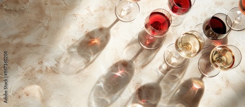 Obraz na płótnie Concept of wine tasting with an arrangement of red, pink, and white wine glasses under sunny lighting. Overhead view with space for text, in a banner format. w salonie