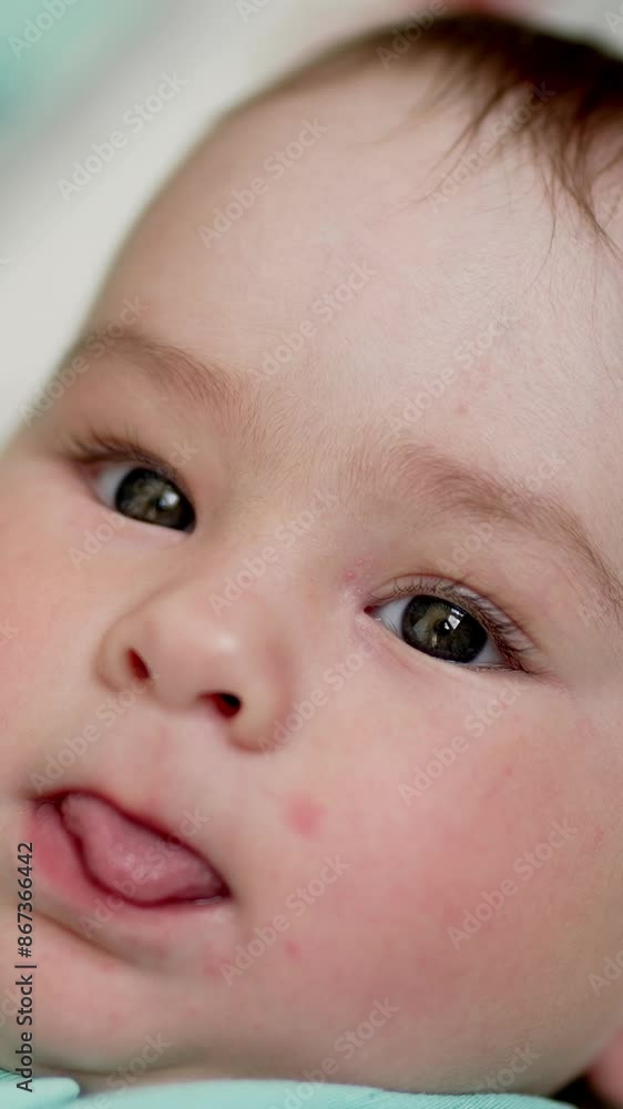 Adorable baby boy put out his tongue and looks at camera. Brown-eyed child smiles sweetly . Close up. Vertical video Adorable baby boy put out his tongue and looks at camera. Brown-eyed child smiles sweetly . Close up. Vertical video