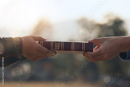 Photos Christian hands giving the Bible and evangelizing someone in a field during a beautiful sunset, church evangelism concept spreading the gospel
