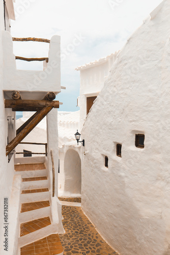 The charming town of Binibeca on Menorca. Narrow streets and white walls of houses with wooden elements, Mediterranean architecture, wonderful Spain. photo