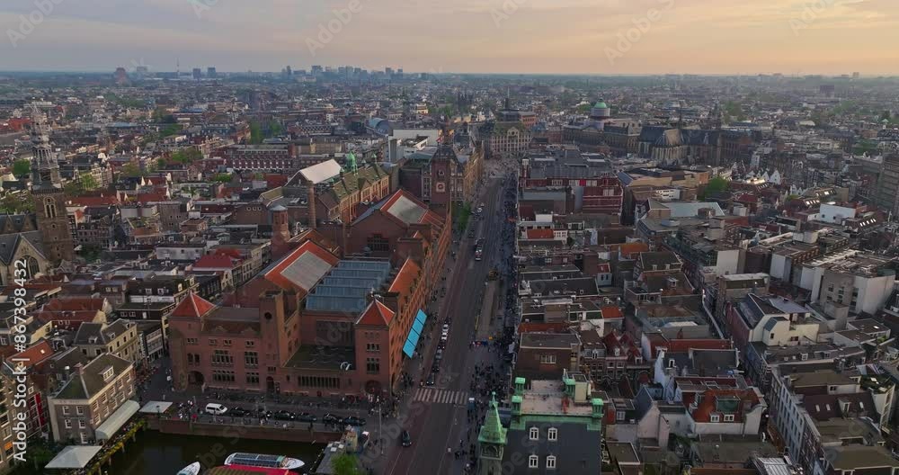 Aerial view of the European tourist city of Amsterdam. A drone flies over the city center at sunset. Establishing shot of the main and famous city in the Netherlands. Narrow canals divide the city Aerial view of the European tourist city of Amsterdam. A drone flies over the city center at sunset. Establishing shot of the main and famous city in the Netherlands. Narrow canals divide the city