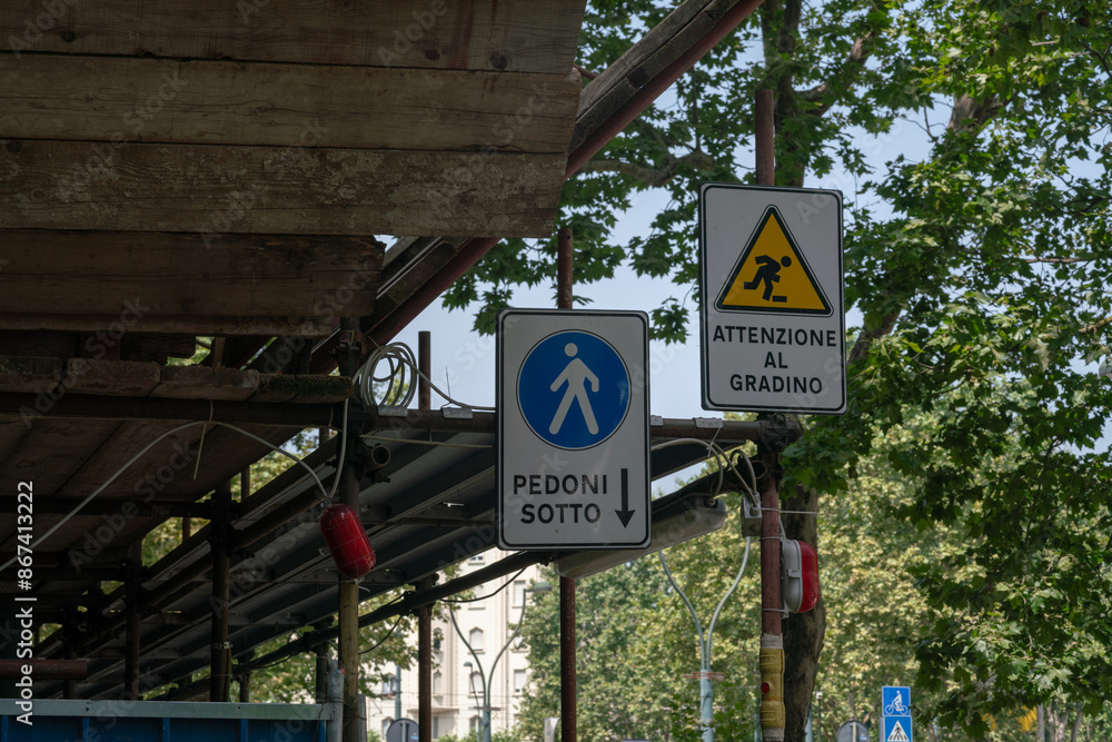 Fototapeta premium construction site building, pedestrian crossing under scaffolding on a construction site, signs indicate the direction and be careful not to trip.