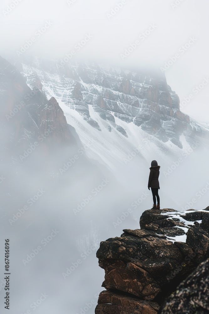 Person on cliff edge facing foggy mountain landscape Person on cliff edge facing foggy mountain landscape