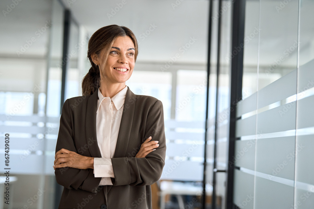 Confident 45 years old woman business owner standing in office. Middle aged businesswoman manager, mature female professional executive, corporate leader wearing suit looking away thinking of success. Confident 45 years old woman business owner standing in office. Middle aged businesswoman manager, mature female professional executive, corporate leader wearing suit looking away thinking of success.