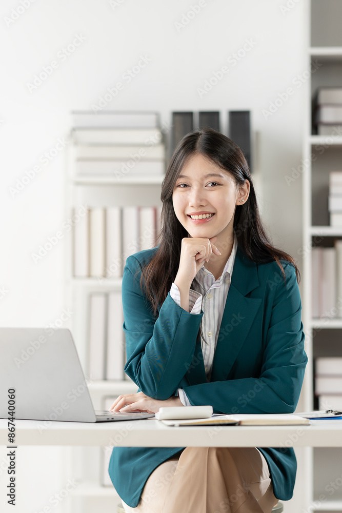 Attractive Asian woman sitting on laptop computer in business office Calculate balances, documents, and check income within the company. vertical picture Attractive Asian woman sitting on laptop computer in business office Calculate balances, documents, and check income within the company. vertical picture