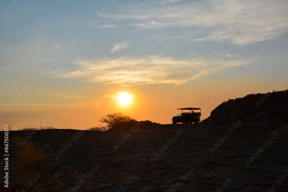 Fototapeta premium Silhouette of a jeep all-terrain vehicle against the background of the evening sky in a desert area. Tourism and summer vacation
