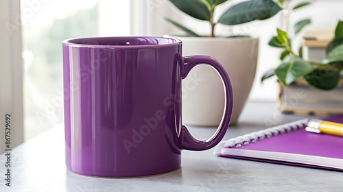 Modern office desk featuring a large purple mug, notepad, and a Ficus plant. photo