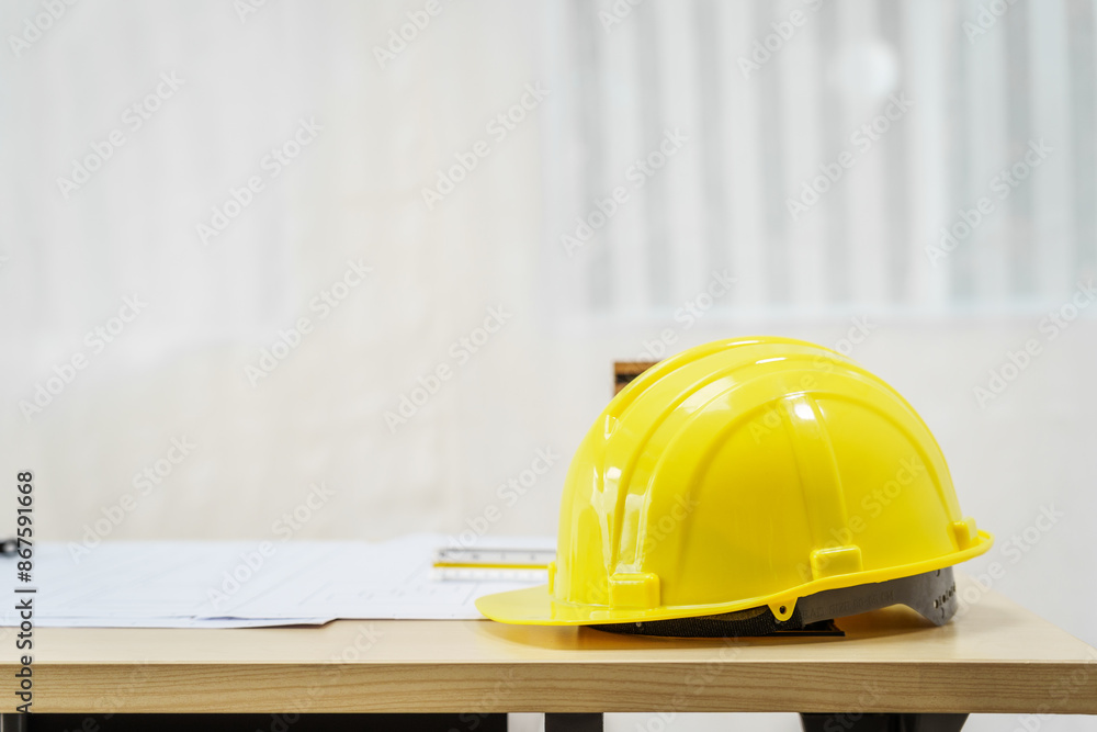 An architect's desk with blueprints and a white hardhat sits empty, ready for the next project. No people are present, highlighting the tools of the trade. An architect's desk with blueprints and a white hardhat sits empty, ready for the next project. No people are present, highlighting the tools of the trade.