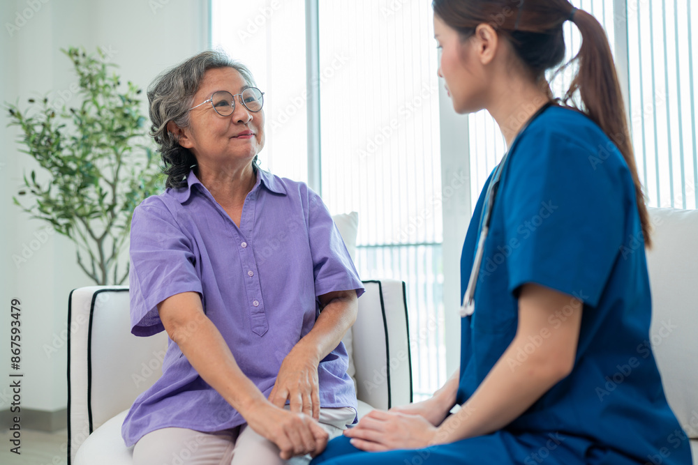 Fototapeta premium Asian young nurse taking care and talking mature female patient sitting on sofa in hospital. Healthcare concept.