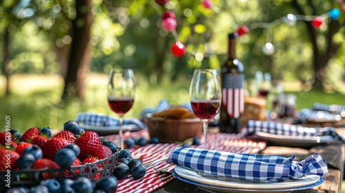 A festive picnic table set with red, white and blue checkered tablecloth, wine, and fruit.