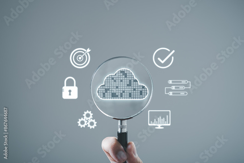 Hand holding magnifying glass with cloud computing icons, representing data analysis, storage, and security in a digital environment. photo