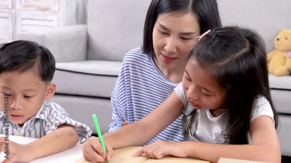 Cheerful Asian mother spend time with two sibling kids teaching homework drawing picture together in living room at home, free time children on holiday bonding happy relationship with mom parenthood Cheerful Asian mother spend time with two sibling kids teaching homework drawing picture together in living room at home, free time children on holiday bonding happy relationship with mom parenthood