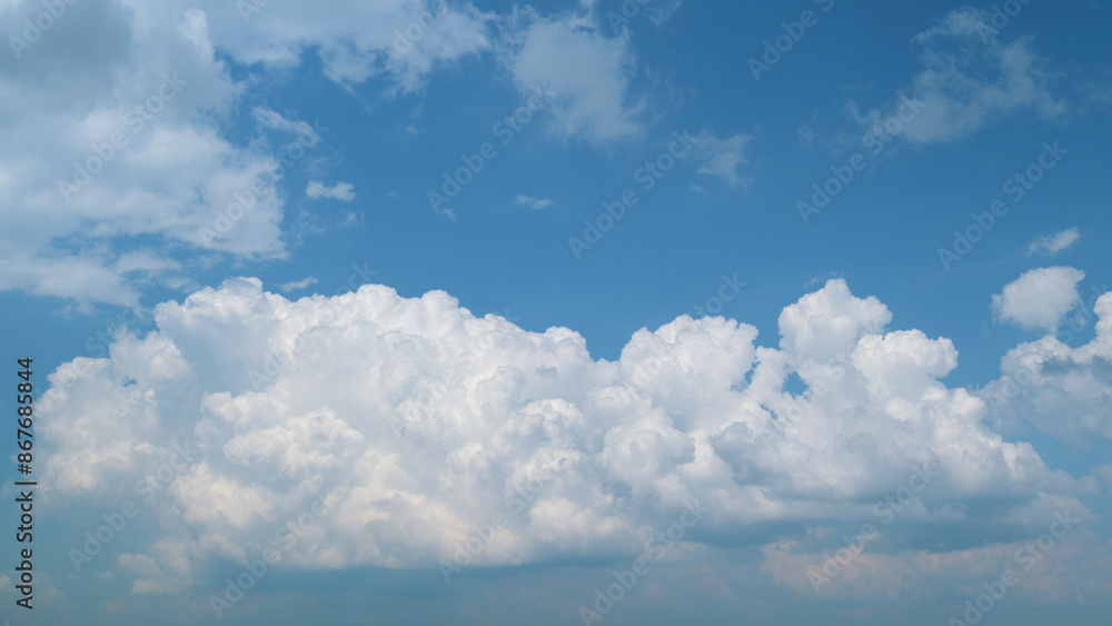 Obraz premium Withe clouds in a blue sky. White fluffy cumulonimbus clouds forming before thunderstorm. Timelapse.