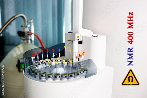 Sample tubes are placed in a tray to be analyzed by an automated NMR spectroscopy at 400 MHz. Additionally, the yellow symbol indicates a warning for high magnetic field strength in the instrument. photo