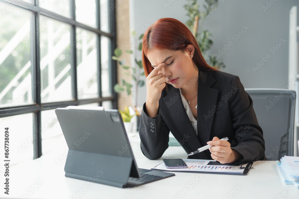 Stressed businesswoman suffering from headache while working on laptop Stressed businesswoman suffering from headache while working on laptop