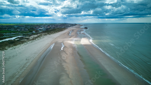 Mesmerizing aerial view of Dunkirk beach captured by a drone! The expansive golden sands and shimmering blue waters of the North Sea offer a breathtaking and tranquil scene, perfect for tourism, trave photo