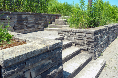 Luxury landscaping with natural stone retaining wall and coping, wide steps and landing.