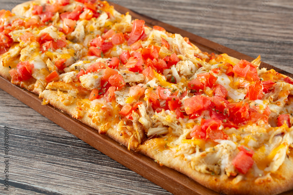 A view of a flatbread appetizer, featuring toppings as chicken, tomato and cheese. A view of a flatbread appetizer, featuring toppings as chicken, tomato and cheese.
