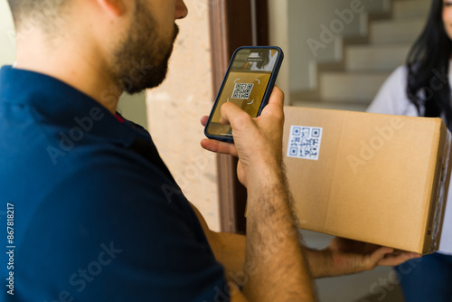 Closeup of a delivery man scanning a QR code with his smartphone while delivering a package to a customer's home photo