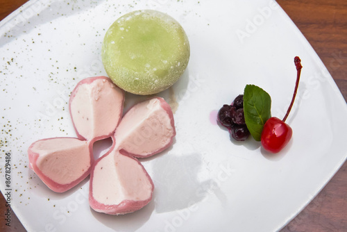 Mochi ice, strawberry and green tea mochi ice accompanied by cherry and blueberries on wooden table photo