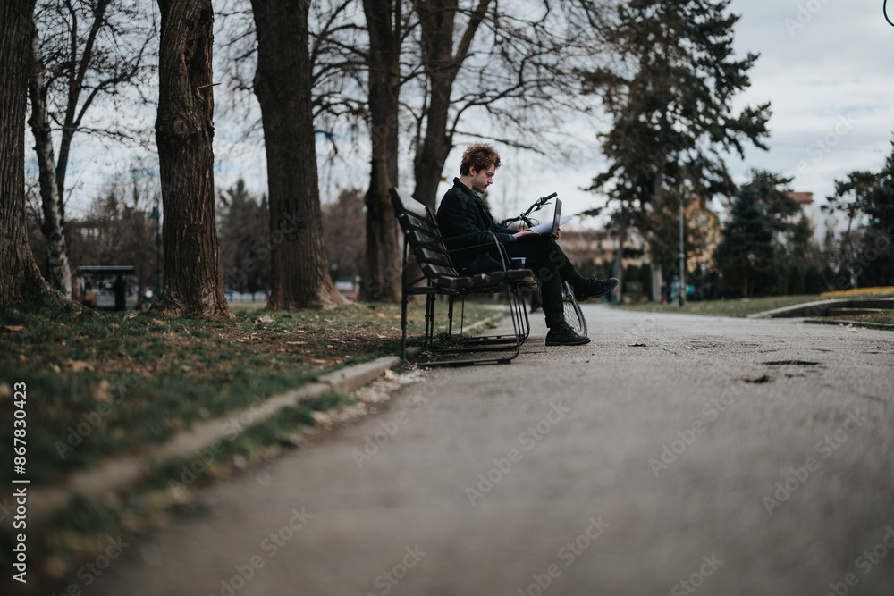 A focused business entrepreneur takes a working break outdoors, seated on a park bench with a bike and laptop. A focused business entrepreneur takes a working break outdoors, seated on a park bench with a bike and laptop.