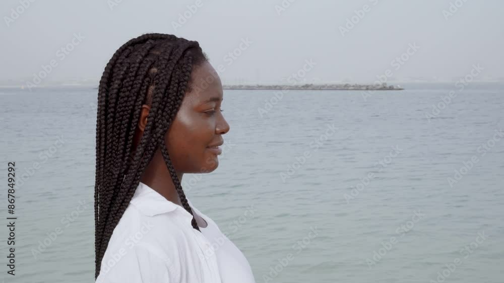 Woman with braids standing at the beach wearing white outfit Woman with braids standing at the beach wearing white outfit